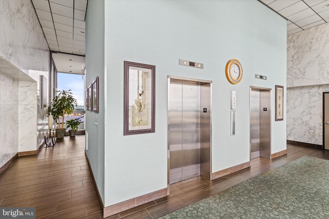 hall featuring elevator and a towering ceiling