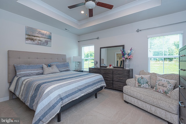 bedroom featuring light carpet, ceiling fan, and a tray ceiling