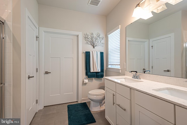 bathroom featuring tile patterned flooring, vanity, a shower with shower door, and toilet