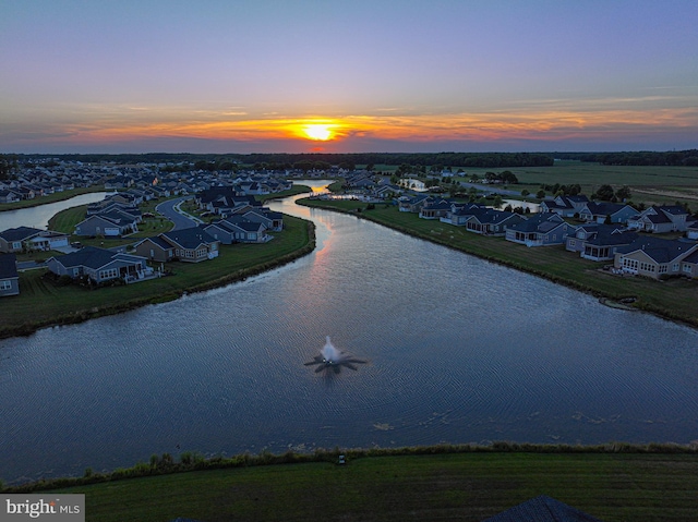 aerial view at dusk featuring a water view