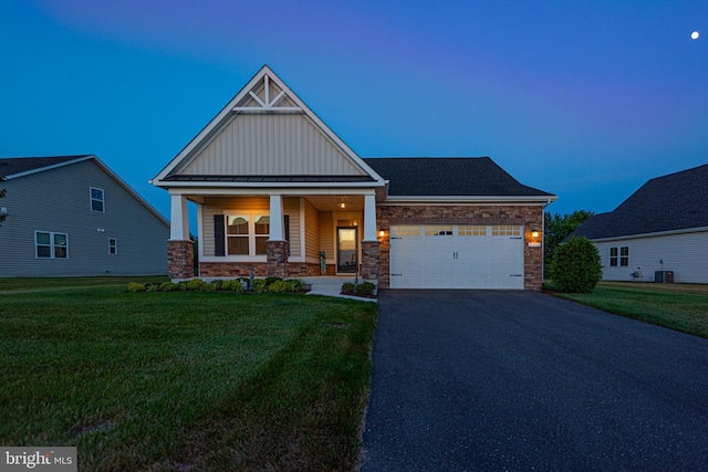 craftsman-style home with a yard, a garage, central air condition unit, and covered porch