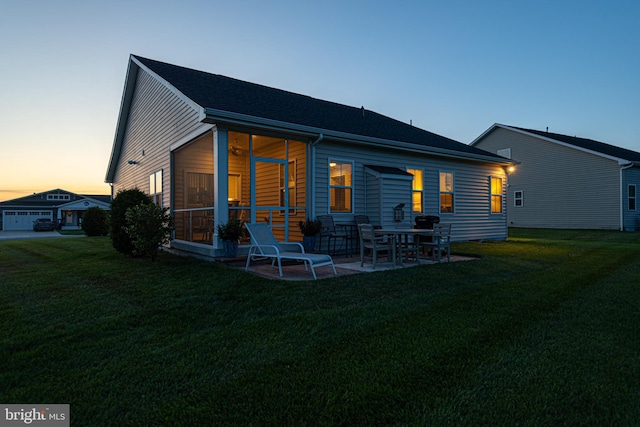 back house at dusk with a yard and a patio area