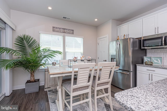 kitchen featuring a breakfast bar, white cabinetry, a center island, dark hardwood / wood-style flooring, and stainless steel appliances