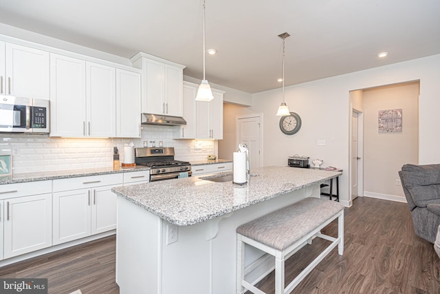 kitchen featuring appliances with stainless steel finishes, pendant lighting, sink, white cabinets, and a center island with sink