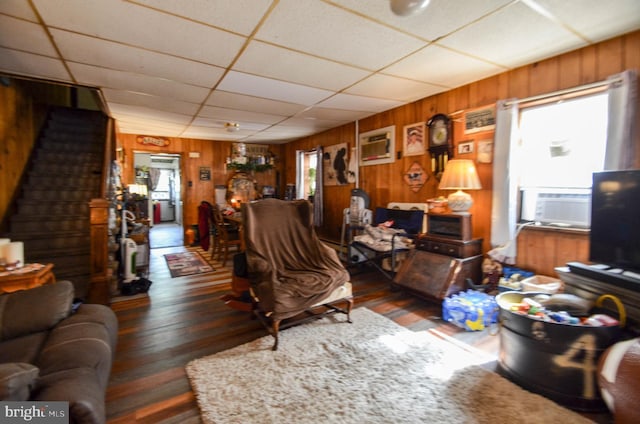 living room with an AC wall unit, a drop ceiling, and cooling unit