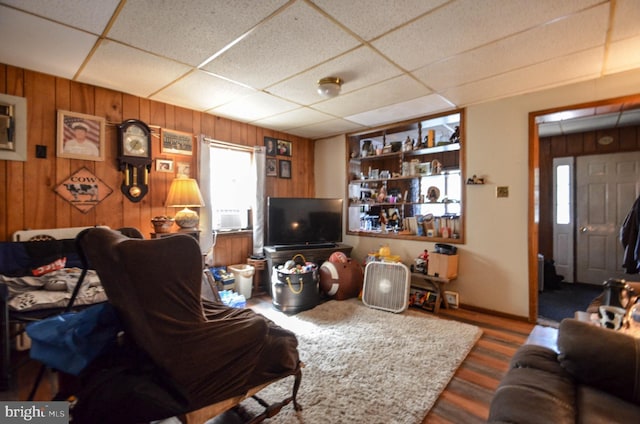 living room with a paneled ceiling and wooden walls