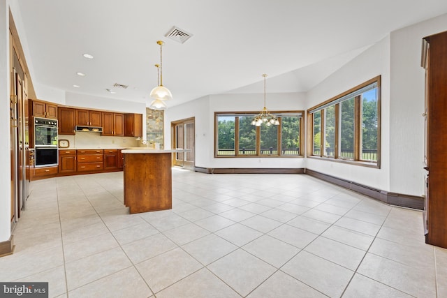 kitchen with an inviting chandelier, black double oven, light tile patterned floors, decorative light fixtures, and a kitchen island