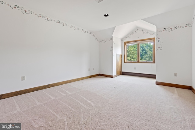 unfurnished room featuring carpet flooring, vaulted ceiling, and a baseboard heating unit