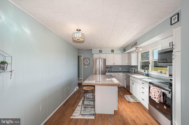 kitchen with a breakfast bar, a center island, white cabinetry, and stainless steel appliances