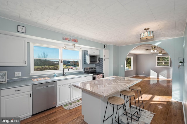 kitchen with stainless steel appliances, ceiling fan, sink, white cabinets, and a center island