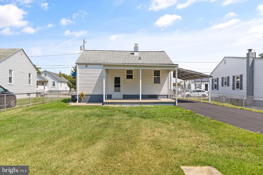 back of property with a yard, central AC unit, and a carport