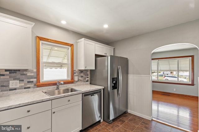 kitchen with white cabinets, dark tile patterned flooring, sink, decorative backsplash, and appliances with stainless steel finishes