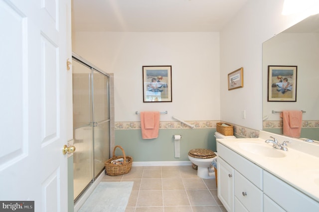 bathroom with tile patterned flooring, vanity, toilet, and a shower with door