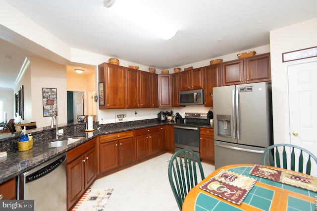 kitchen with stainless steel appliances, dark stone counters, and sink