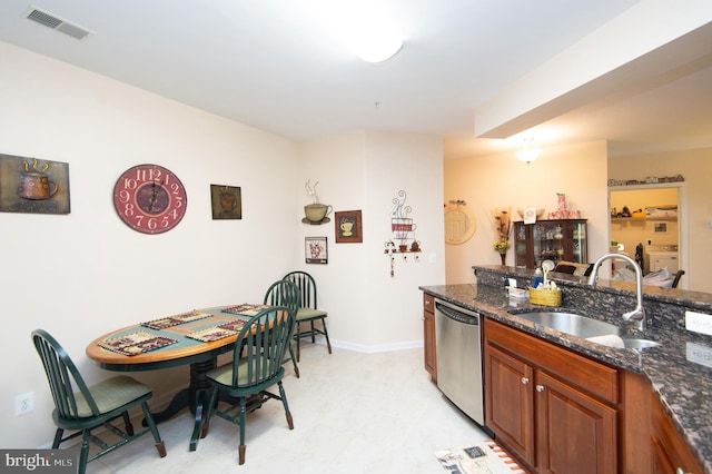 kitchen with dark stone countertops, separate washer and dryer, sink, and stainless steel dishwasher