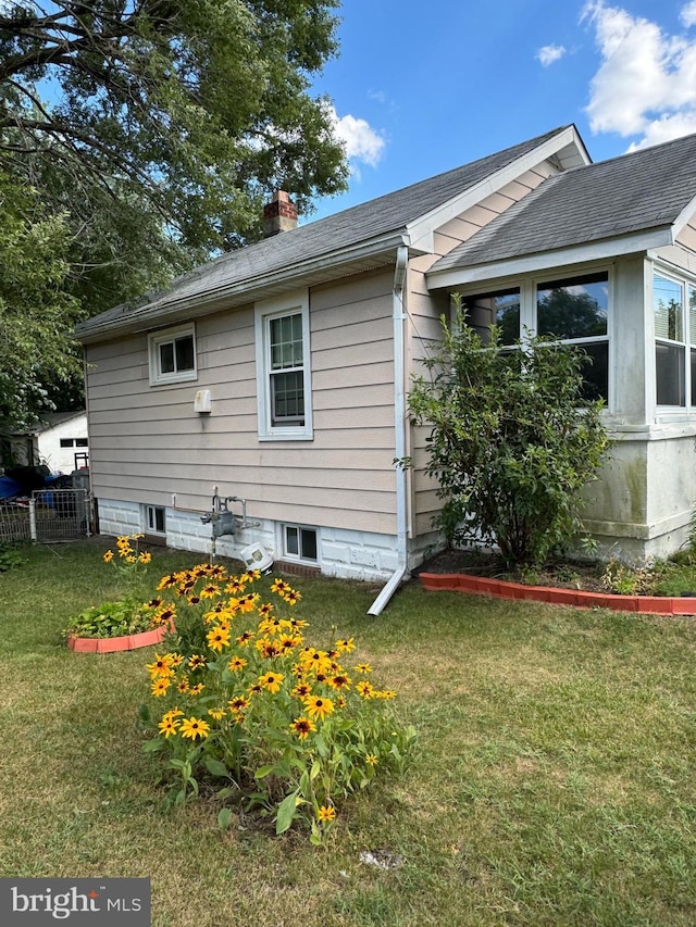 view of property exterior with roof with shingles, a yard, a chimney, and fence