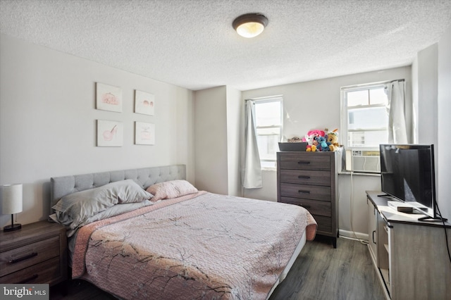 bedroom featuring cooling unit, dark hardwood / wood-style floors, and a textured ceiling