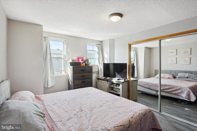 bedroom featuring a closet, a textured ceiling, and dark hardwood / wood-style floors