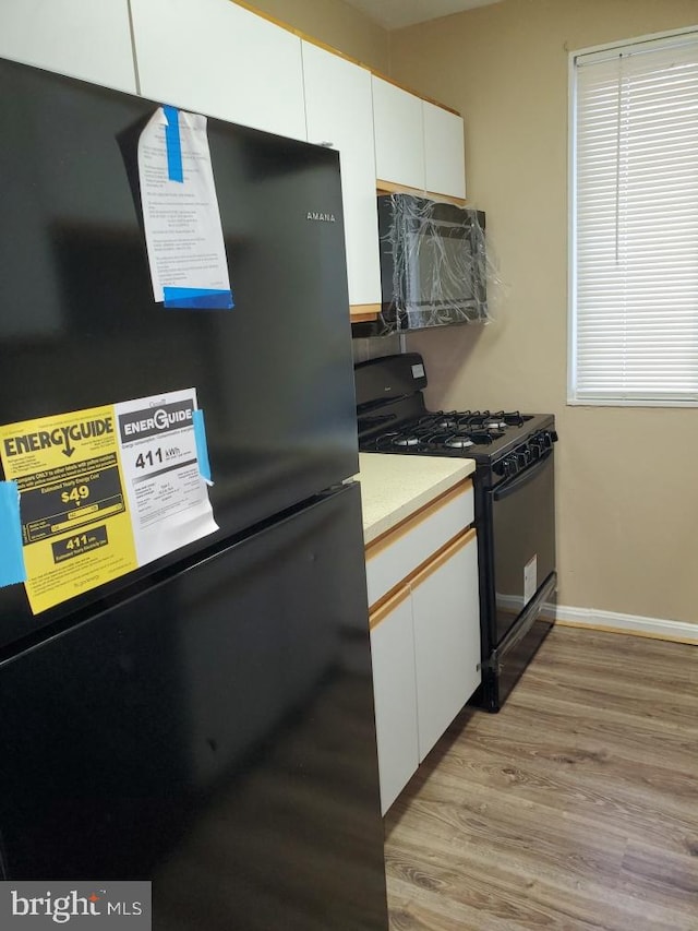 kitchen featuring light wood-type flooring, white cabinetry, and black appliances