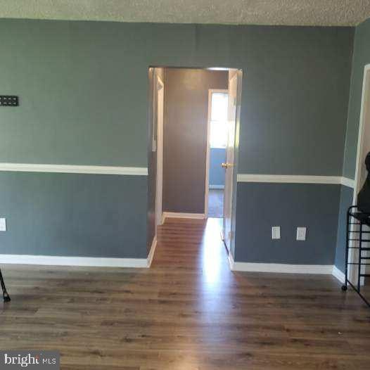 empty room with a textured ceiling and dark hardwood / wood-style floors