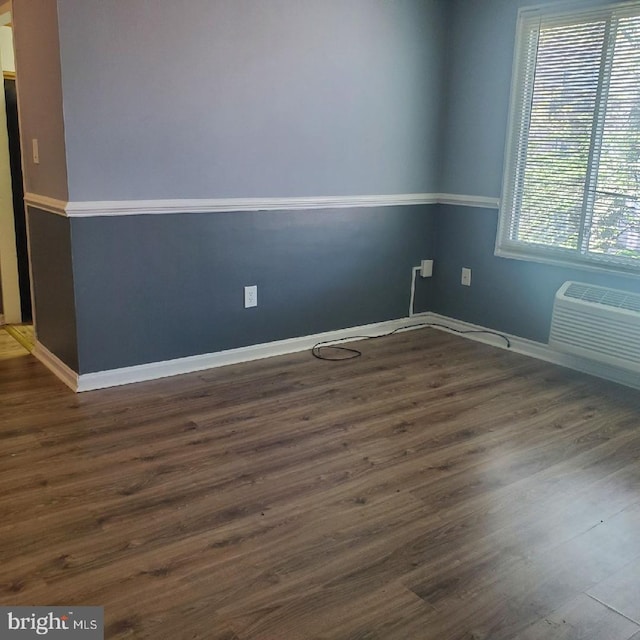 empty room with a wall mounted air conditioner and dark wood-type flooring