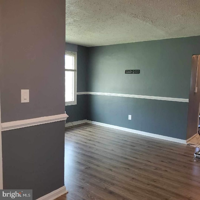 spare room with dark hardwood / wood-style flooring and a textured ceiling