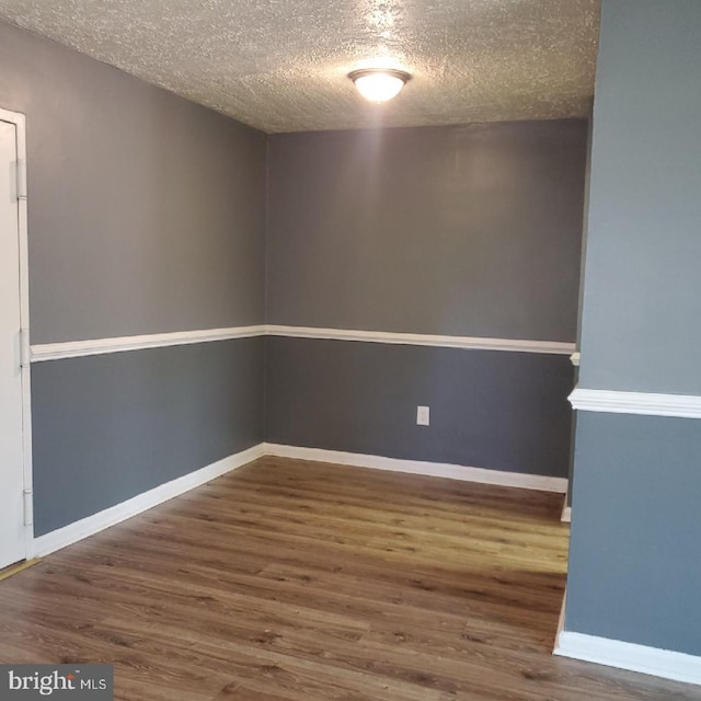 empty room with dark hardwood / wood-style floors and a textured ceiling