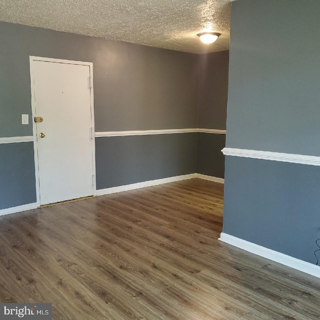 spare room featuring dark hardwood / wood-style floors and a textured ceiling