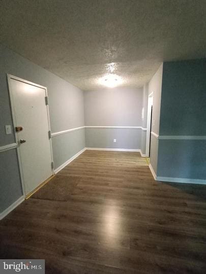 spare room featuring a textured ceiling and dark wood-type flooring