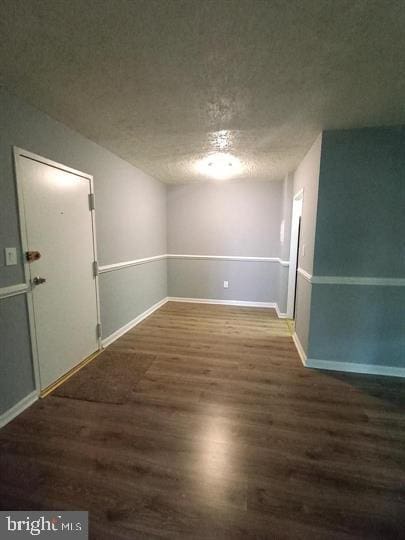 spare room featuring a textured ceiling and dark hardwood / wood-style floors