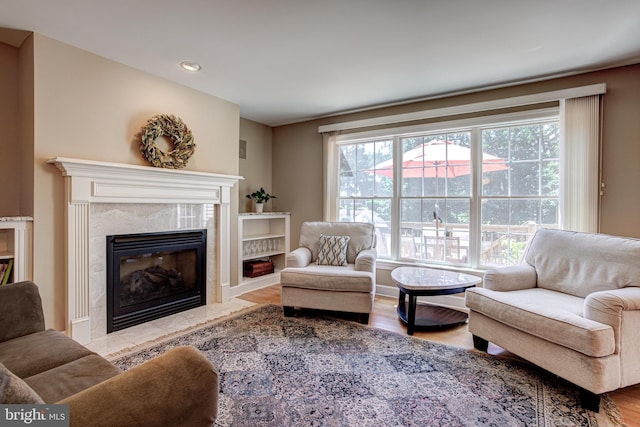 living room featuring a tile fireplace and light wood-type flooring