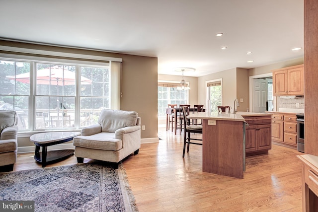 living room featuring light wood-type flooring, an inviting chandelier, and sink