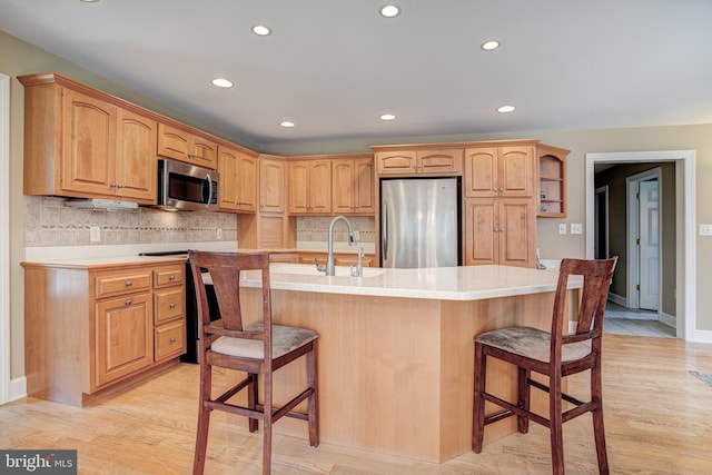 kitchen featuring stainless steel appliances, a kitchen island with sink, a breakfast bar area, and sink