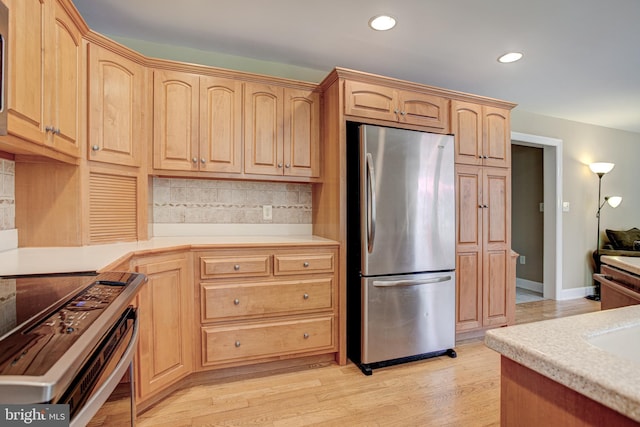 kitchen featuring light brown cabinetry, stainless steel appliances, tasteful backsplash, and light hardwood / wood-style floors