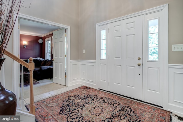 foyer entrance featuring light tile patterned floors and crown molding