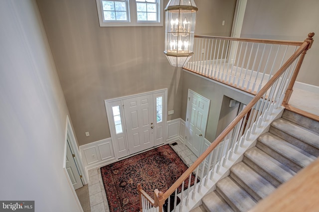 tiled entrance foyer featuring a towering ceiling and a chandelier