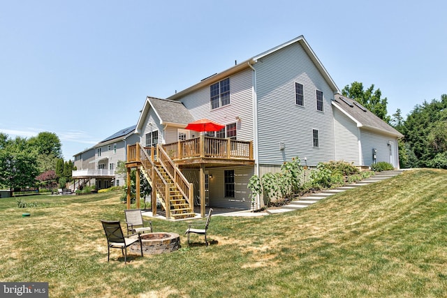 back of property with a fire pit, a deck, and a lawn