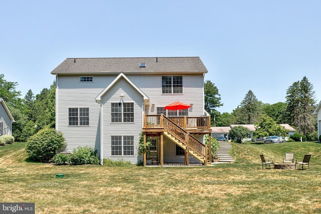 back of house featuring a lawn, a deck, and an outdoor fire pit