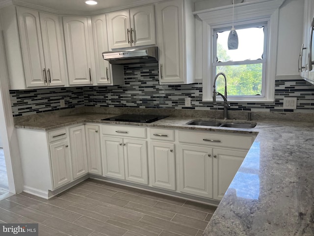 kitchen featuring white cabinetry, sink, decorative light fixtures, and black electric stovetop