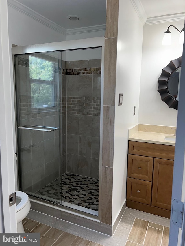 bathroom featuring vanity, toilet, ornamental molding, and walk in shower