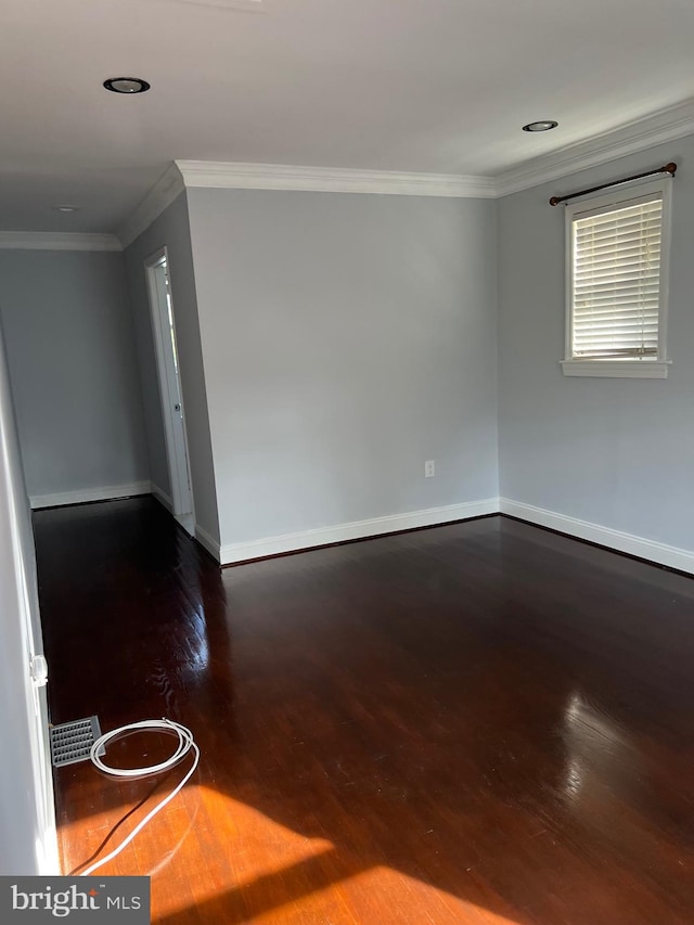 empty room featuring dark hardwood / wood-style flooring and ornamental molding