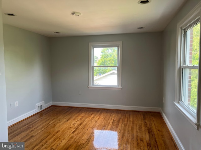 unfurnished room with hardwood / wood-style floors and a healthy amount of sunlight