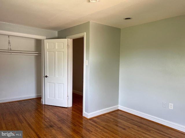 unfurnished bedroom with a closet and dark wood-type flooring