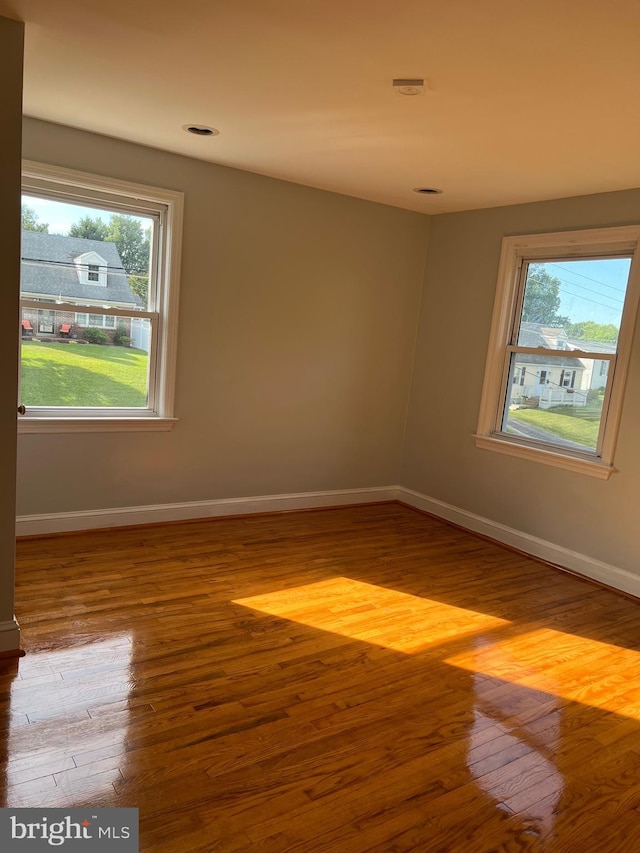 spare room with hardwood / wood-style floors and plenty of natural light