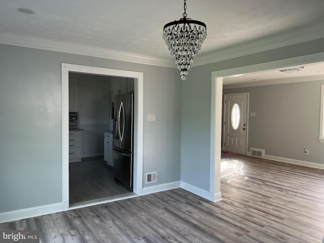 unfurnished dining area with wood-type flooring, a textured ceiling, an inviting chandelier, and crown molding