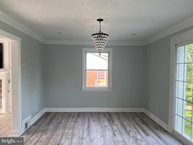 unfurnished dining area with a chandelier, hardwood / wood-style floors, plenty of natural light, and ornamental molding