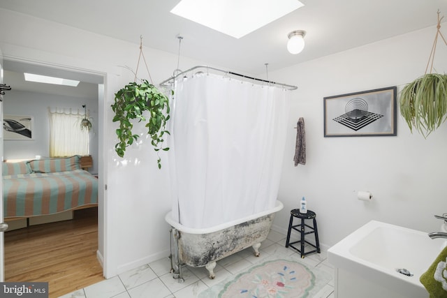 bathroom featuring separate shower and tub, a skylight, and sink