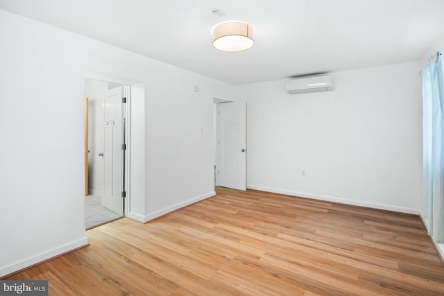 unfurnished room featuring a wall mounted AC and light wood-type flooring