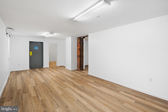 spare room with a wall mounted air conditioner and light hardwood / wood-style flooring