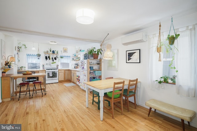 dining room with a wall unit AC, plenty of natural light, and light hardwood / wood-style floors